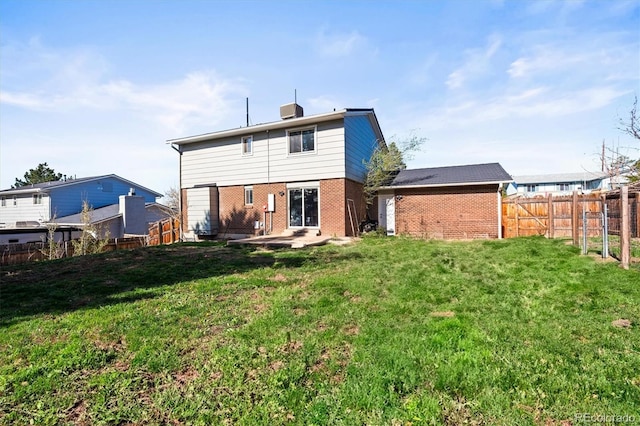 back of house featuring a fenced backyard, a patio, brick siding, and a lawn