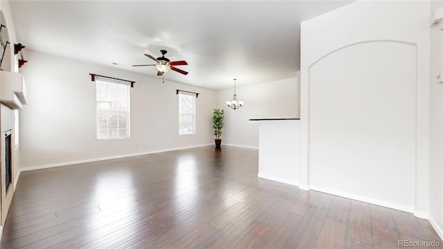 unfurnished living room with a fireplace, ceiling fan with notable chandelier, wood finished floors, and baseboards