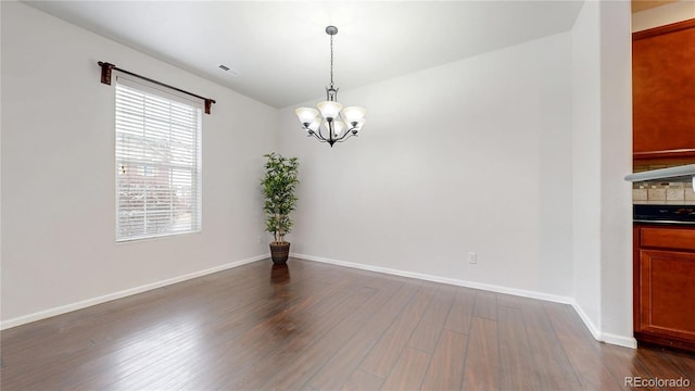 unfurnished dining area featuring dark wood-style floors, a chandelier, visible vents, and baseboards