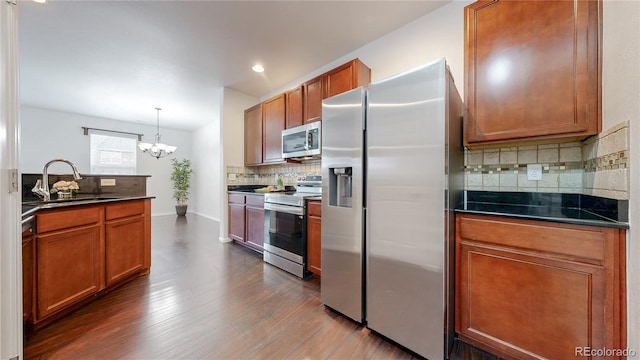 kitchen featuring dark wood-style floors, a sink, stainless steel appliances, dark countertops, and brown cabinets