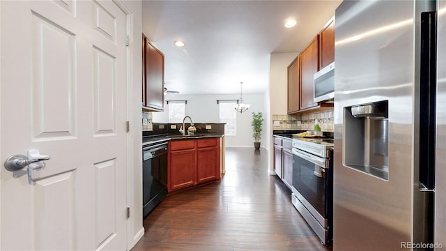 kitchen featuring dark countertops, tasteful backsplash, dark wood-style floors, stainless steel appliances, and a sink