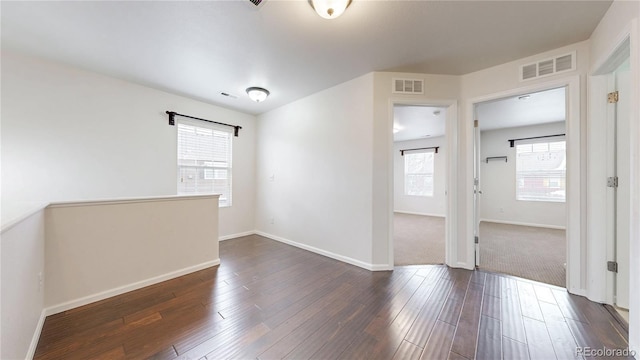 spare room featuring dark wood finished floors, baseboards, and visible vents