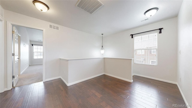 unfurnished room featuring visible vents, baseboards, and wood finished floors