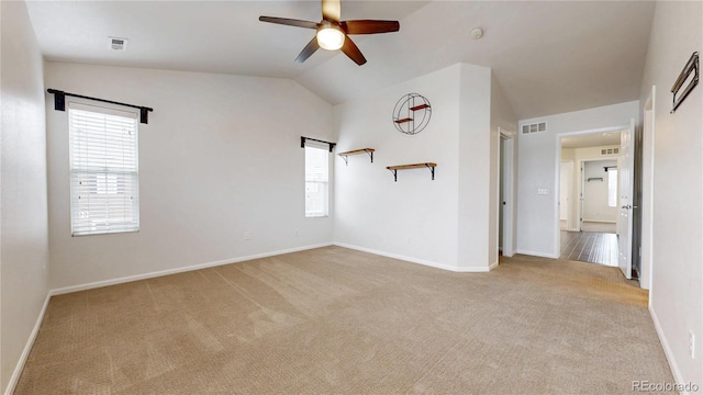 carpeted spare room with visible vents, baseboards, ceiling fan, and vaulted ceiling