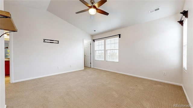 empty room with visible vents, lofted ceiling, light colored carpet, and ceiling fan