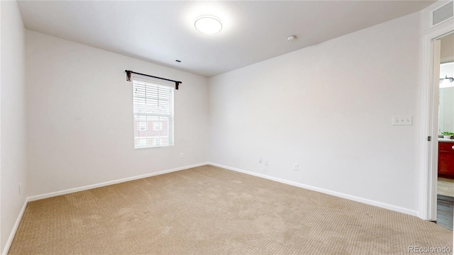 carpeted spare room with visible vents and baseboards