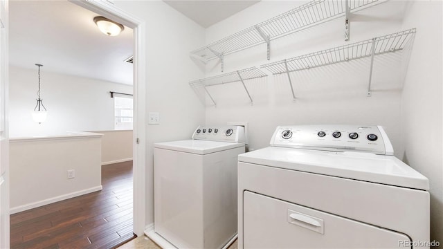 clothes washing area featuring laundry area, independent washer and dryer, baseboards, and wood finished floors