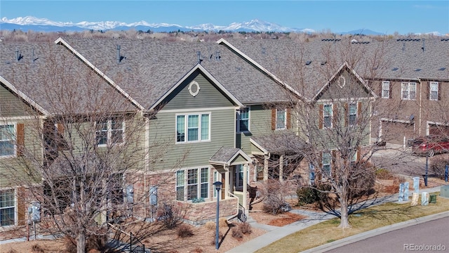 multi unit property featuring a mountain view and roof with shingles