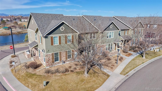 view of front facade featuring a residential view, a water view, and stone siding