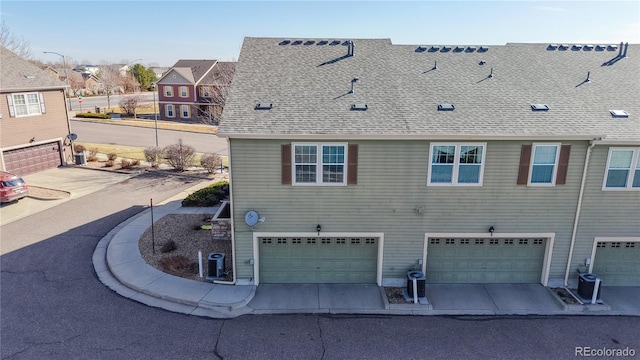 view of home's exterior featuring an attached garage and a shingled roof