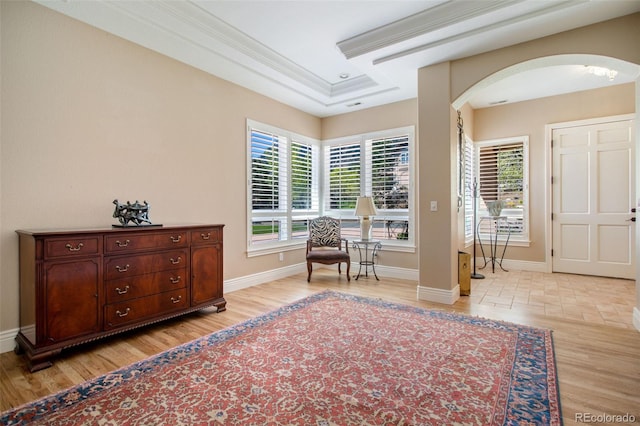 sitting room with light wood-type flooring, crown molding, and a raised ceiling