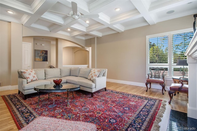 living room featuring coffered ceiling, hardwood / wood-style flooring, ceiling fan, ornamental molding, and beam ceiling