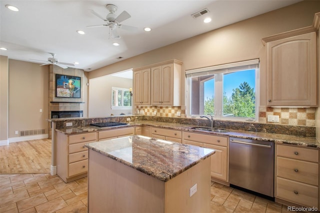 kitchen featuring light brown cabinetry, sink, stainless steel appliances, and a kitchen island