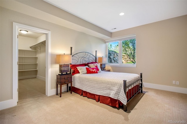 carpeted bedroom featuring a walk in closet and a closet