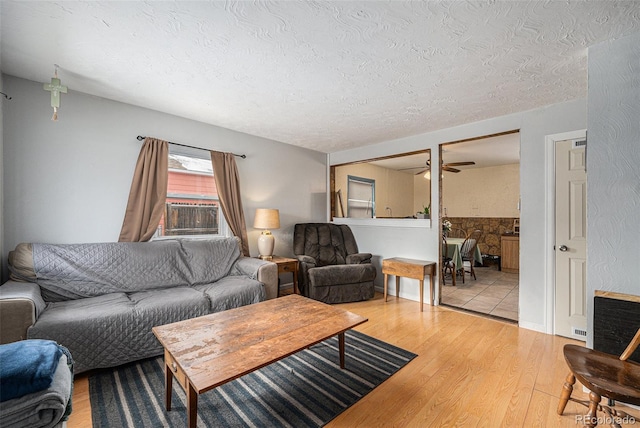 living area with cooling unit, a textured ceiling, wood finished floors, and a ceiling fan