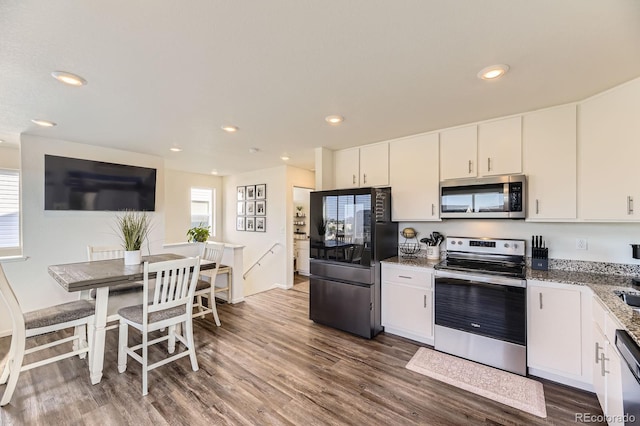 18270 E 51st Pl, Denver, CO 80249 - kitchen with stainless steel appliances, dark wood finished floors, light stone counters, white cabinetry, and recessed lighting