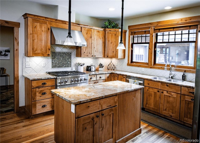 kitchen with stainless steel appliances, wood finished floors, a sink, and a kitchen island