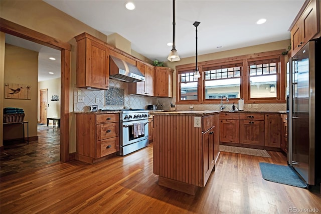 kitchen with wall chimney exhaust hood, dark wood-type flooring, high end appliances, and backsplash