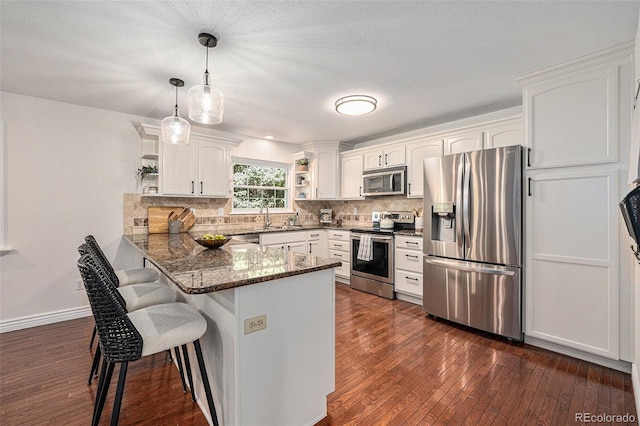 10247 W Roxbury Pl, Littleton, CO 80127 - kitchen with stainless steel appliances, open shelves, a peninsula, white cabinetry, and dark wood finished floors