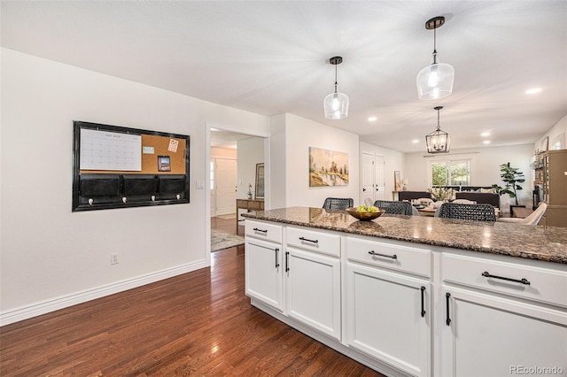 10247 W Roxbury Pl, Littleton, CO 80127 - kitchen with dark wood finished floors, white cabinets, open floor plan, pendant lighting, and dark stone counters