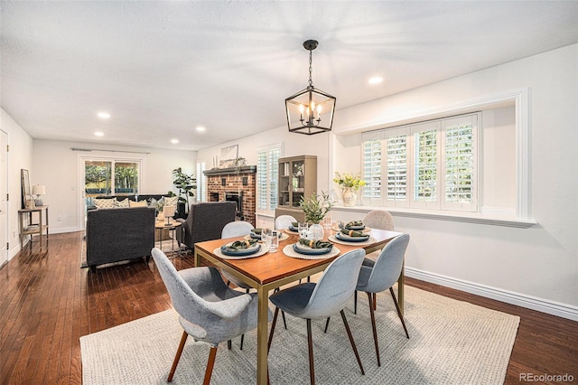 10247 W Roxbury Pl, Littleton, CO 80127 - dining area with dark wood-style flooring, baseboards, recessed lighting, a brick fireplace, and a chandelier