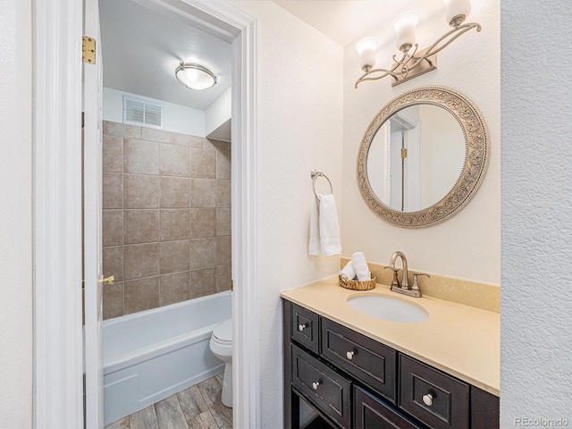 full bathroom with vanity, tiled shower / bath, and toilet