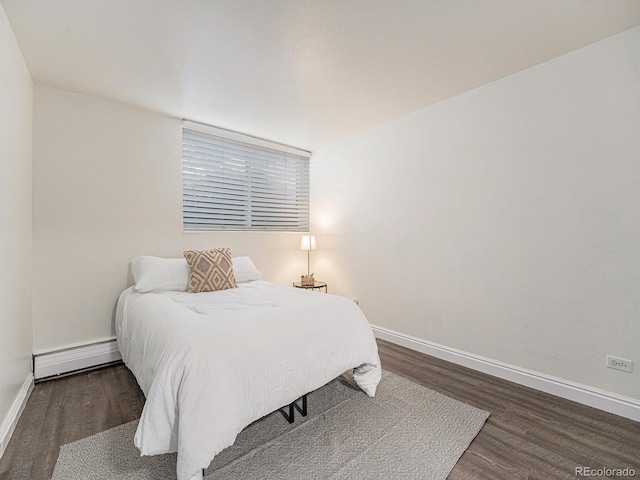 bedroom with a baseboard heating unit and dark hardwood / wood-style flooring