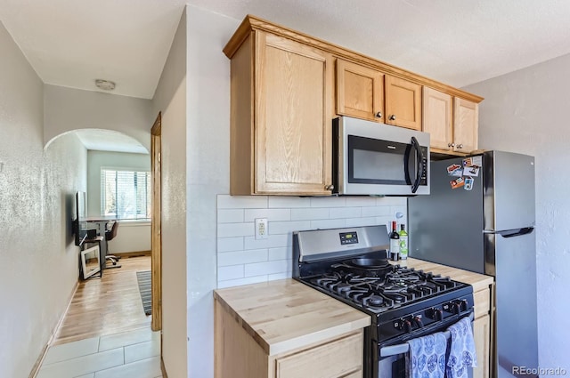 3061 W 18th Ave, Denver, CO 80204 - kitchen featuring stainless steel appliances, arched walkways, tasteful backsplash, light countertops, and baseboards