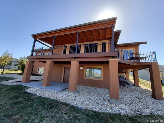 back of house featuring a wooden deck, a patio area, and stucco siding