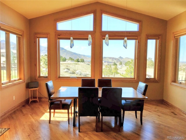 dining area with visible vents, baseboards, lofted ceiling, light wood-style floors, and a mountain view