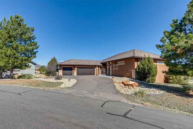 view of front facade with a garage, fence, aphalt driveway, and stucco siding