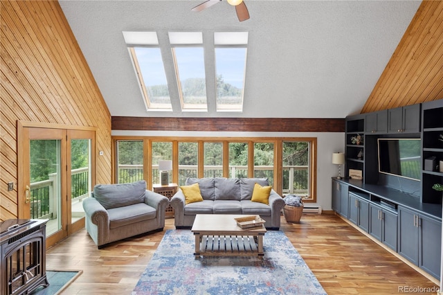 living room featuring light wood finished floors, high vaulted ceiling, wood walls, a ceiling fan, and a baseboard heating unit