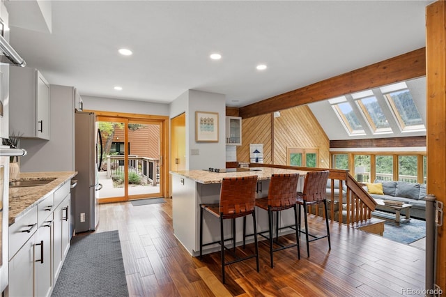 kitchen featuring freestanding refrigerator, a breakfast bar area, dark wood-style floors, a center island, and recessed lighting
