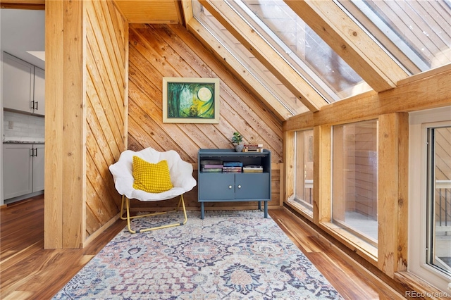 sitting room featuring wooden walls, vaulted ceiling, and wood finished floors