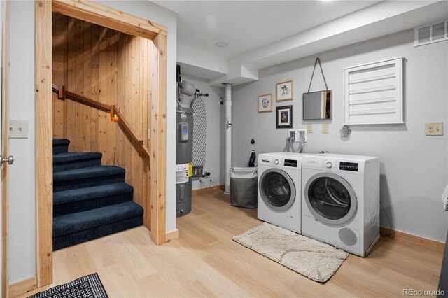 washroom with independent washer and dryer, laundry area, light wood-style flooring, and electric water heater