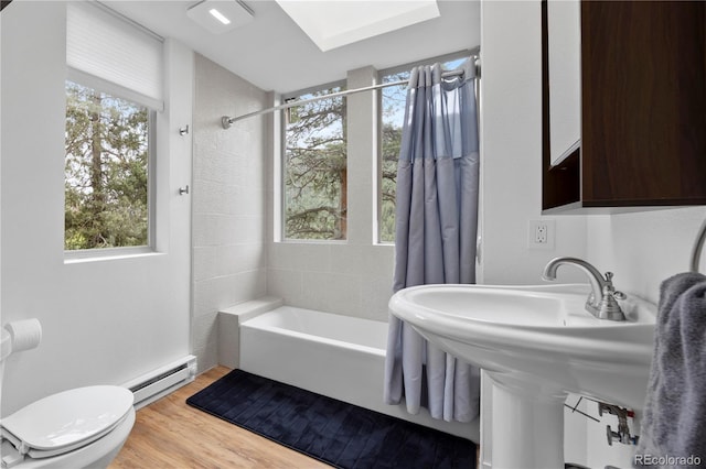 full bath with wood finished floors, a baseboard heating unit, shower / bath combo, and toilet