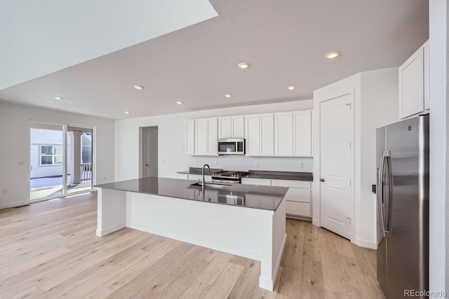 kitchen with a kitchen island with sink, white cabinets, sink, light wood-type flooring, and appliances with stainless steel finishes