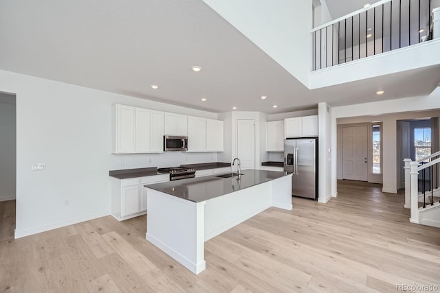 kitchen featuring white cabinets, appliances with stainless steel finishes, a kitchen island with sink, and sink