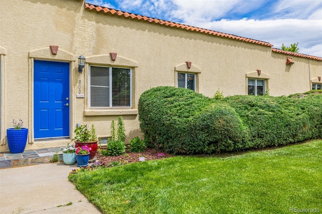 1800 Grove St, Denver, CO 80204 - doorway to property featuring stucco siding and a lawn