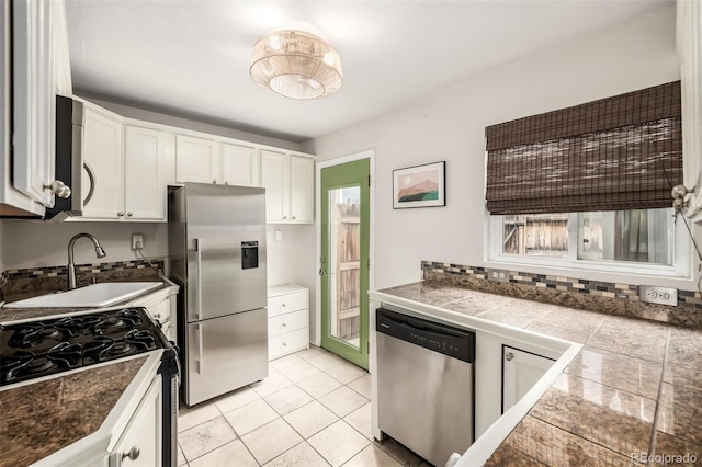 1800 Grove St, Denver, CO 80204 - kitchen with stainless steel appliances, tile countertops, a sink, white cabinetry, and light tile patterned flooring