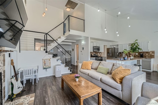 10064 Owens St, Broomfield, CO 80021 - living room featuring a towering ceiling, stairs, dark wood-type flooring, and baseboards