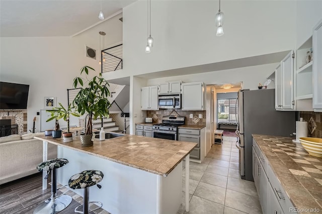 10064 Owens St, Broomfield, CO 80021 - kitchen featuring appliances with stainless steel finishes, high vaulted ceiling, decorative backsplash, open shelves, and a sink