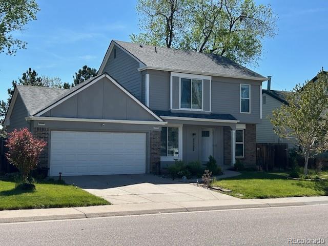 10064 Owens St, Broomfield, CO 80021 - traditional-style home featuring an attached garage, brick siding, driveway, and a front yard