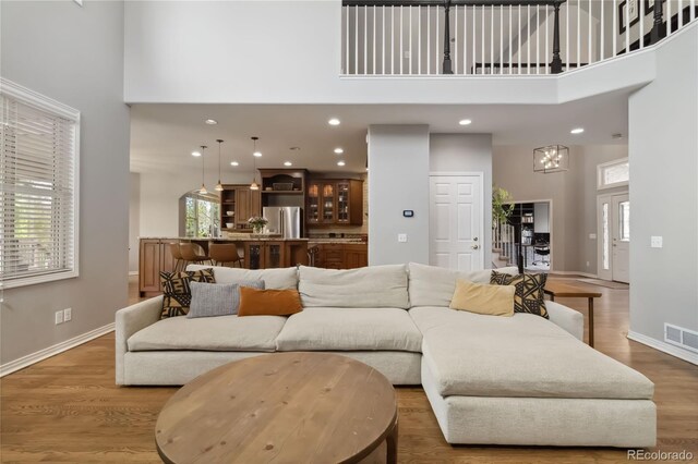 living area featuring a high ceiling, baseboards, wood finished floors, and recessed lighting