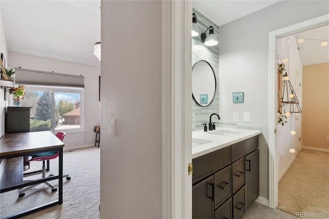 bathroom featuring baseboards and double vanity