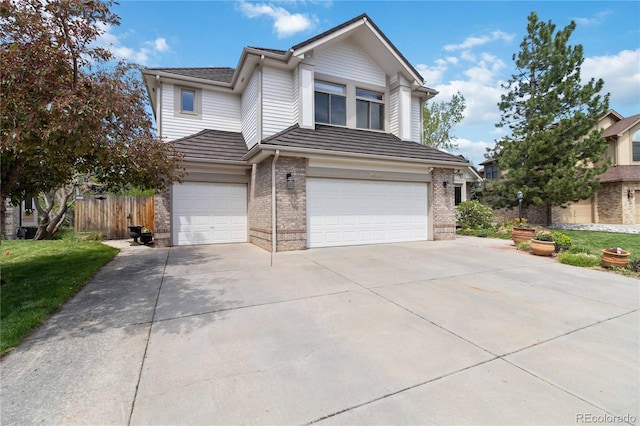 view of front facade featuring brick siding, an attached garage, concrete driveway, and fence