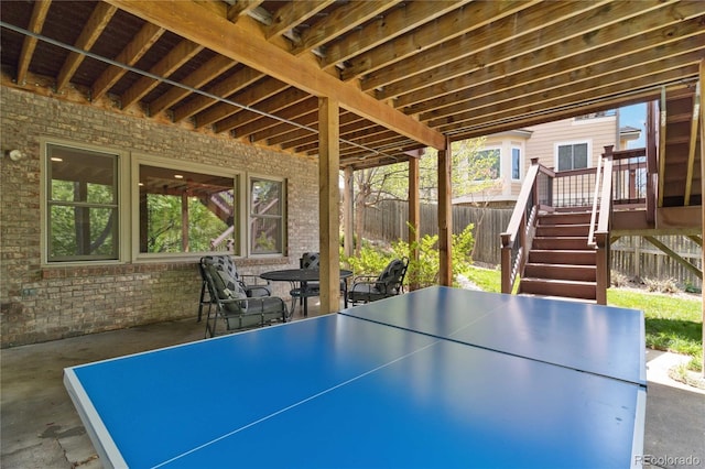 view of patio featuring fence, stairs, a wooden deck, and outdoor dining area