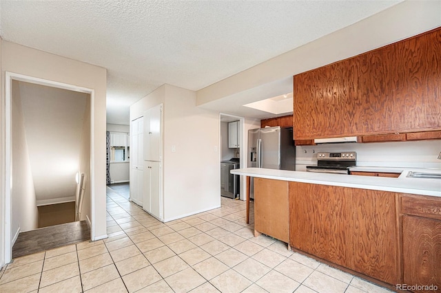 12662 W Virginia Ave, Lakewood, CO 80228 - kitchen featuring a peninsula, electric stove, light countertops, light tile patterned flooring, and washer / clothes dryer