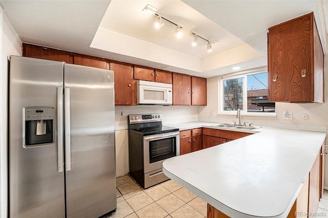 12662 W Virginia Ave, Lakewood, CO 80228 - kitchen featuring a peninsula, a sink, brown cabinetry, light countertops, and appliances with stainless steel finishes