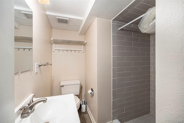 12662 W Virginia Ave, Lakewood, CO 80228 - full bathroom with toilet, visible vents, a sink, tiled shower, and a textured wall
